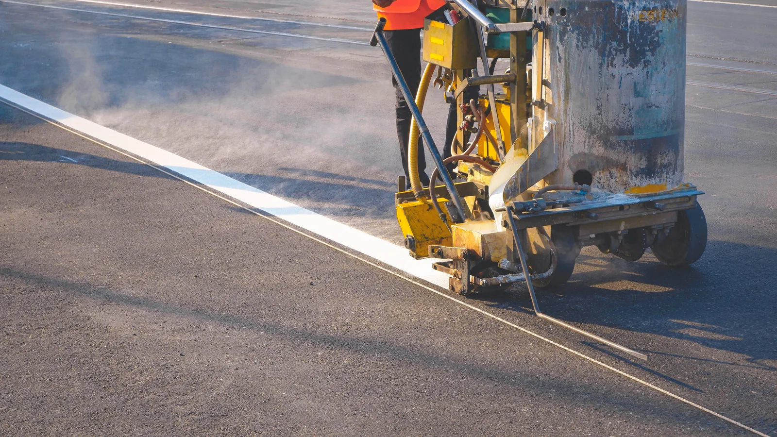 Line striping machine laying down a fresh white line on asphalt